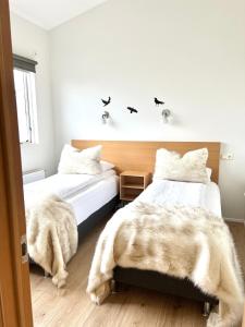 two beds in a bedroom with white walls at Lónið Apartments in Höfn