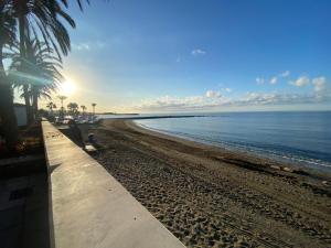 una playa de arena con palmeras y el océano en Marbella Espacioso Apartamento de 180 m2 Primera Línea de Playa y Centro Ciudad con Barco opcional, en Marbella