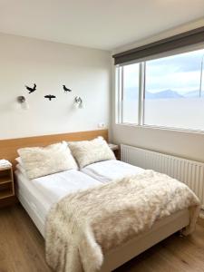 um quarto com uma cama e uma janela com pássaros na parede em Lónið Apartments em Höfn