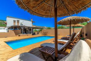 uma villa com uma piscina com cadeiras e um guarda-sol em Countryhouse Villa with pool & private parking em Heraclião