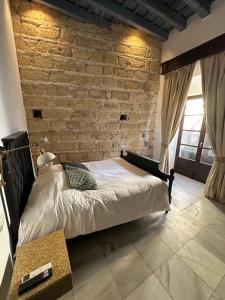 Cama en habitación con pared de ladrillo en Casa Jaramago en Jerez de la Frontera