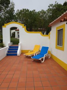 two chairs sitting on a patio with a house at Sondela Self Catering in São Martinho do Porto
