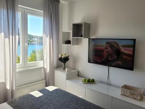 a bedroom with a tv on a wall with a window at Vista Porto Apartment in Mali Lošinj