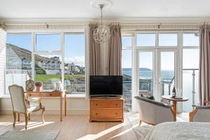 a bedroom with a bed and a tv and a desk at Watersmeet Hotel in Woolacombe
