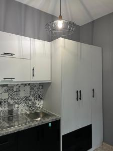 una cocina con armarios blancos y fregadero en O' Kipos, en Mithimna