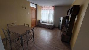 a living room with a table and a kitchen with a refrigerator at Carosvi Home in Lima