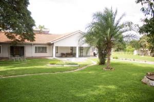 a house with a palm tree in the yard at Amazing Guest House in Harare