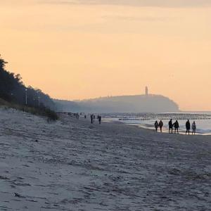 un grupo de personas caminando por la playa en Domki Energetyk en Pogorzelica