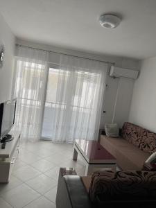 a living room with a couch and a tv at Arber apartments Zeqiraj in Shëngjin