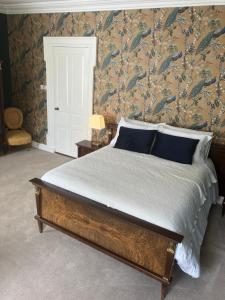 Schlafzimmer mit einem Bett mit blauen Kissen und Tapeten in der Unterkunft Noan Country House B&B in Cashel