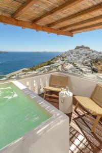 un balcón con bañera de hidromasaje, sillas y el océano en Oneiro Luxury Suites-Adults Only en Astipalea