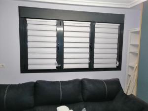 - un canapé noir dans le salon doté d'une fenêtre dans l'établissement Apartamento Florida-Natura Oviedo, à Oviedo