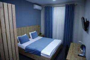 Schlafzimmer mit einem Bett mit blauen Kissen und einem Tisch in der Unterkunft Apple Hotel 小苹果酒店 FREE Airport Service in Taschkent