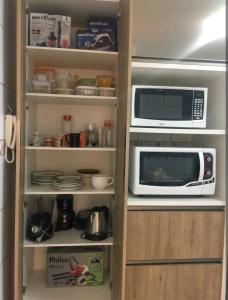 un armario de cocina con microondas y otros artículos de cocina en Apartamento em Balneário Camboriú, en Balneário Camboriú