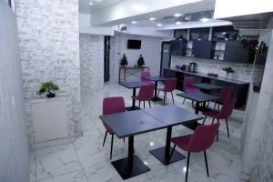 ein Restaurant mit Tischen und rosa Stühlen in einem Zimmer in der Unterkunft Apple Hotel 小苹果酒店 FREE Airport Service in Taschkent