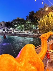 a large yellow dinosaur sitting next to a body of water at MUNIS Hotel lyabi houz in Bukhara