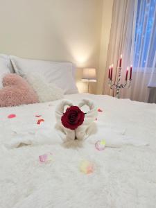 a white bed with a rose and a stuffed animal on it at Albina apartman in Eger