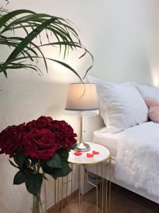 a vase of red roses on a table next to a bed at Albina apartman in Eger
