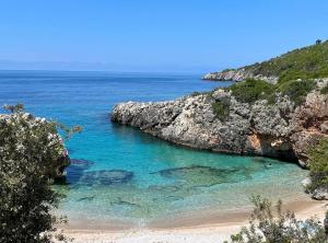 a view of a beach with blue water and rocks at Camping Aquariumm in Himare