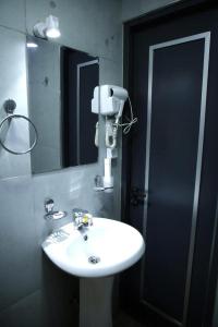 ein Badezimmer mit einem weißen Waschbecken und einem Spiegel in der Unterkunft Apple Hotel 小苹果酒店 FREE Airport Service in Taschkent