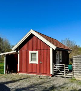 un granero rojo con una puerta blanca y una valla en Holiday house in nature-filled Vidja, near Stockholm City, en Farsta