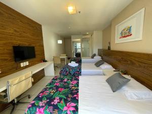um quarto de hotel com três camas e uma televisão de ecrã plano em V1114 Flat com WI-FI exclusivo, academia e piscinas em Brasília