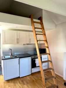 una escalera que conduce a una cocina con armarios blancos en Holiday house in nature-filled Vidja, near Stockholm City, en Farsta