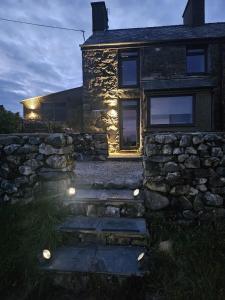 una casa de piedra con luces en el lateral. en cosy cottage in snowdonia en Brynkir