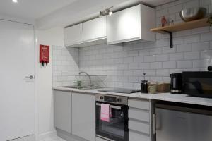 una cucina bianca con piano cottura e forno a microonde di Garden Apartment by Kahuna Stays 