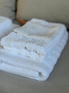 una pila de toallas blancas sentadas en una cama en Holiday house in nature-filled Vidja, near Stockholm City, en Farsta