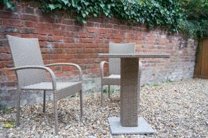 due sedie e un tavolo di fronte a un muro di mattoni di Garden Apartment by Kahuna Stays 