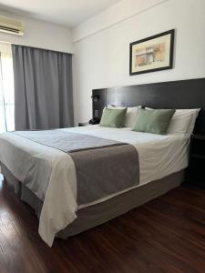 ブエノスアイレスにあるDuomi Hotel Buenos Airesのベッドルーム1室(大型ベッド1台、白いシーツ、緑の枕付)
