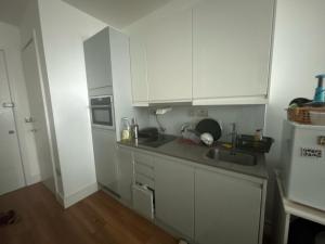 una cocina con armarios blancos y fregadero en Bath Road Slough Home Stay en Slough