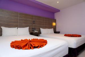 two beds in a hotel room with orange sheets at Hotel Kavia in Cancún