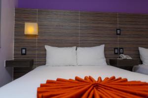 Un dormitorio con una cama grande con una manta naranja. en Hotel Kavia en Cancún