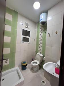 een badkamer met een toilet, een wastafel en een bad bij Blue Umbrella in Muscat