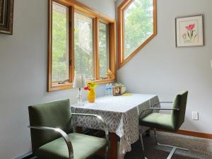 a dining room table with two chairs and two windows at Sunny Peace in Harwinton