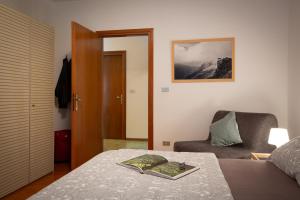 タルヴィージオにあるLa Casa di Carmenのベッドルーム1室(ベッド1台、椅子、本付)