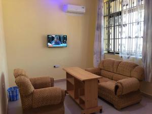 ein Wohnzimmer mit 2 Stühlen und einem TV an der Wand in der Unterkunft St Paul's Hostels Buhabugali Kigoma in Kigoma