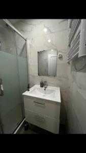 La salle de bains blanche est pourvue d'un lavabo et d'une douche. dans l'établissement Modern studio - Le Bourget Ideal JO 2024, au Bourget