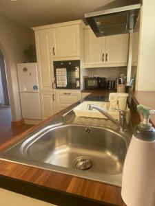 una cocina con fregadero de acero inoxidable y armarios blancos en Kilmore Beach Apartment en Tralee