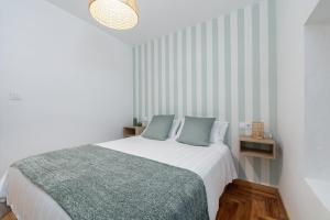 Dormitorio blanco con cama con almohadas azules en Mahalo Home, en Porriño
