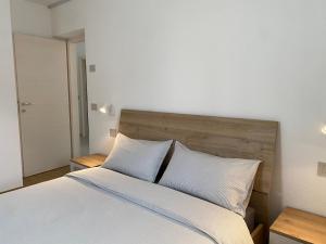 een slaapkamer met een bed met witte lakens en kussens bij Casa di Maggie 1 in Carisolo