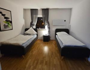 two beds in a small room with wooden floors at M&L Wohnen 2 in Essen