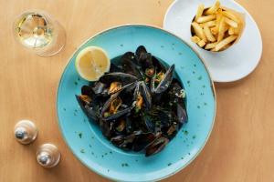 a blue plate of mussels and a plate of fries at Watersmeet Hotel in Woolacombe