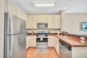 a kitchen with white cabinets and a stainless steel refrigerator at 3BR Condo - Near Disney Balcony Pool Hot tub in Orlando