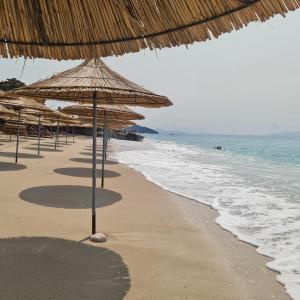 a beach with straw umbrellas and the ocean at Sunset House in Vlorë