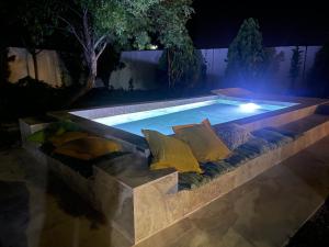 una piscina por la noche con almohadas y un sofá en HEARTS & PONIES Apartamentos con piscinas privadas cerca de la Warner en Chinchón