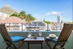 een balkon met 2 stoelen en een tafel met wijnglazen bij The Palm Flats - Palm Paradise in Kaapstad