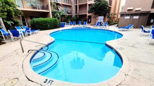 una gran piscina con sillas y sillas azules en Beachview 105 Condominium Condo, en South Padre Island